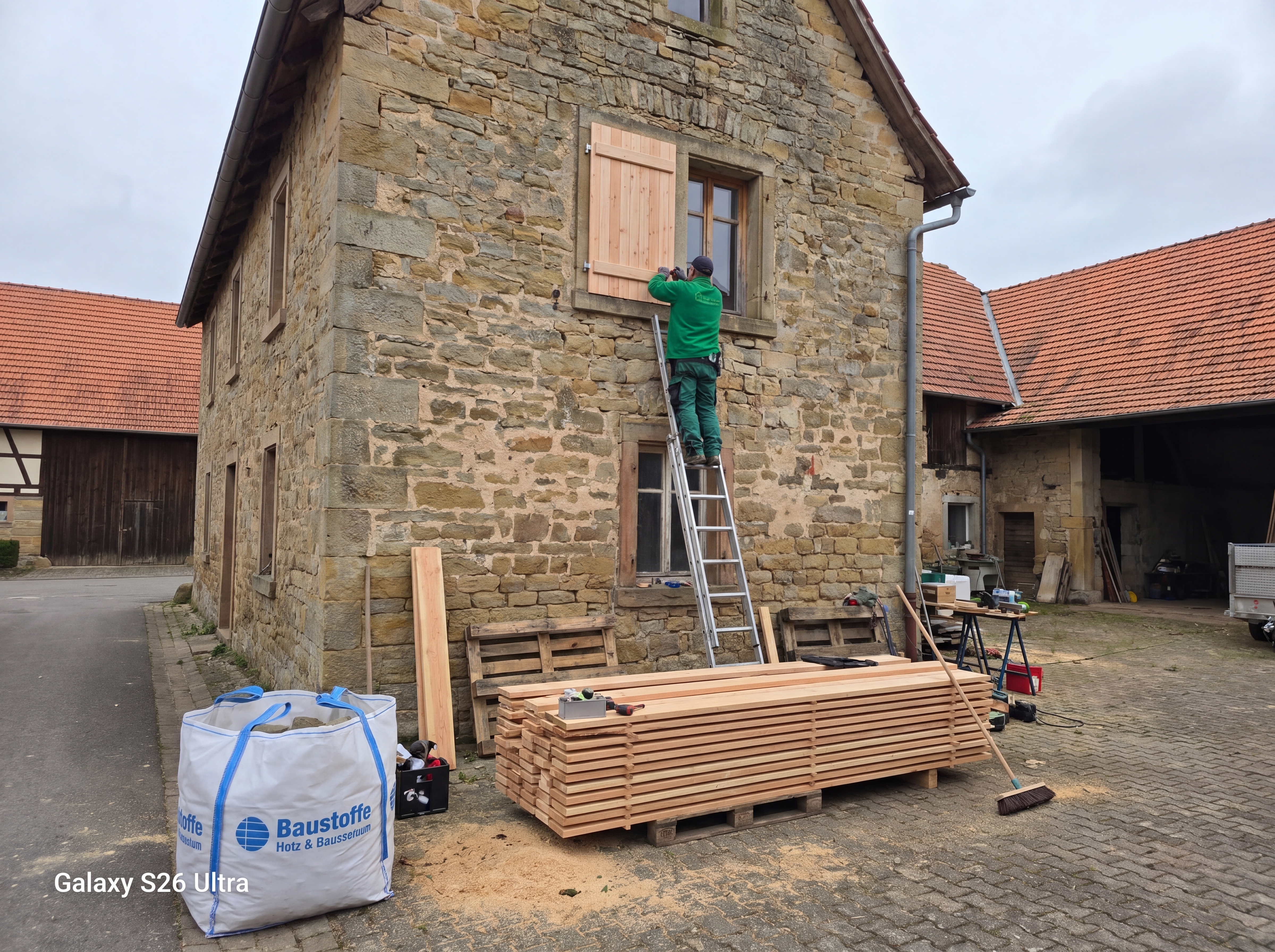Fensterladen-Montage an historischem Steinhaus